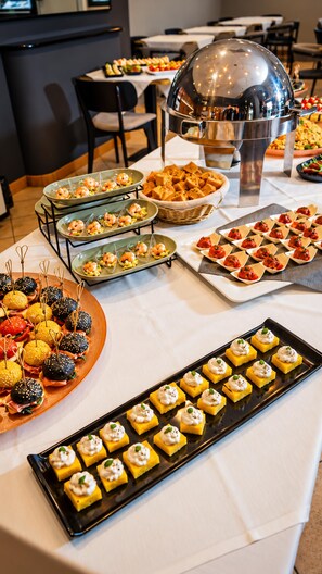 Una mesa de buffet con distintos alimentos, como camarones, hamburguesas y postres.