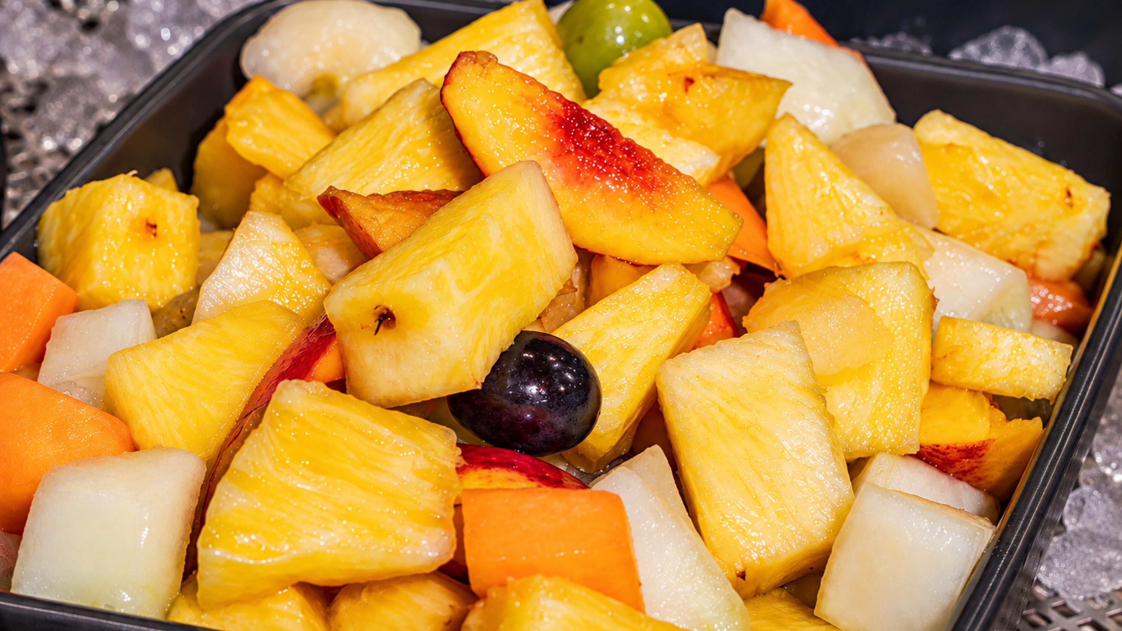 Un plateau contenant un assortiment de fruits, notamment de l’ananas, de la mangue et des kiwis.