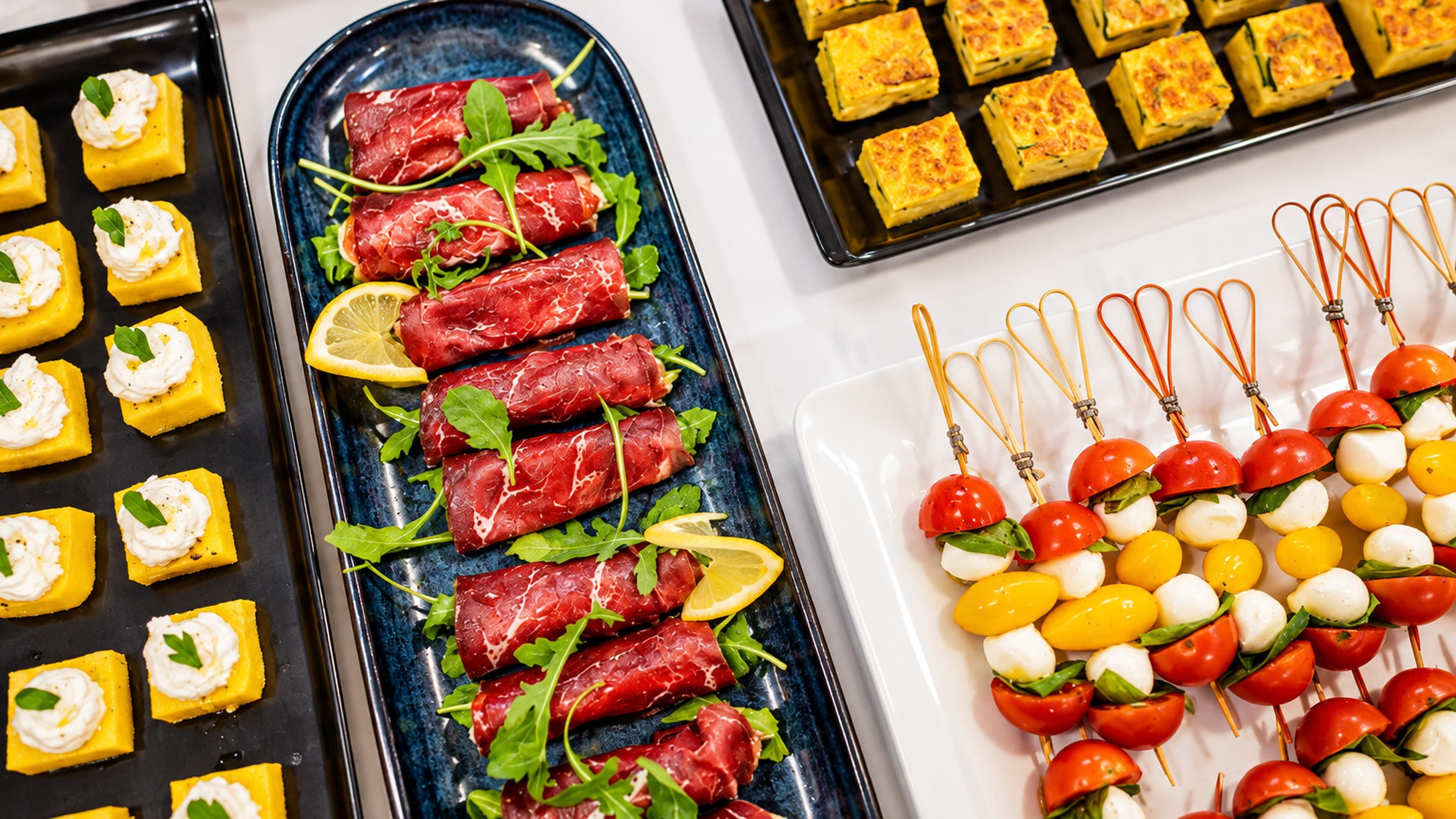A variety of food items including rolled meat, cheese, and vegetables on plates.