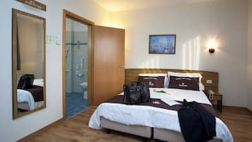 A hotel room with a bed, a bathroom, a mirror, and a painting on the wall.