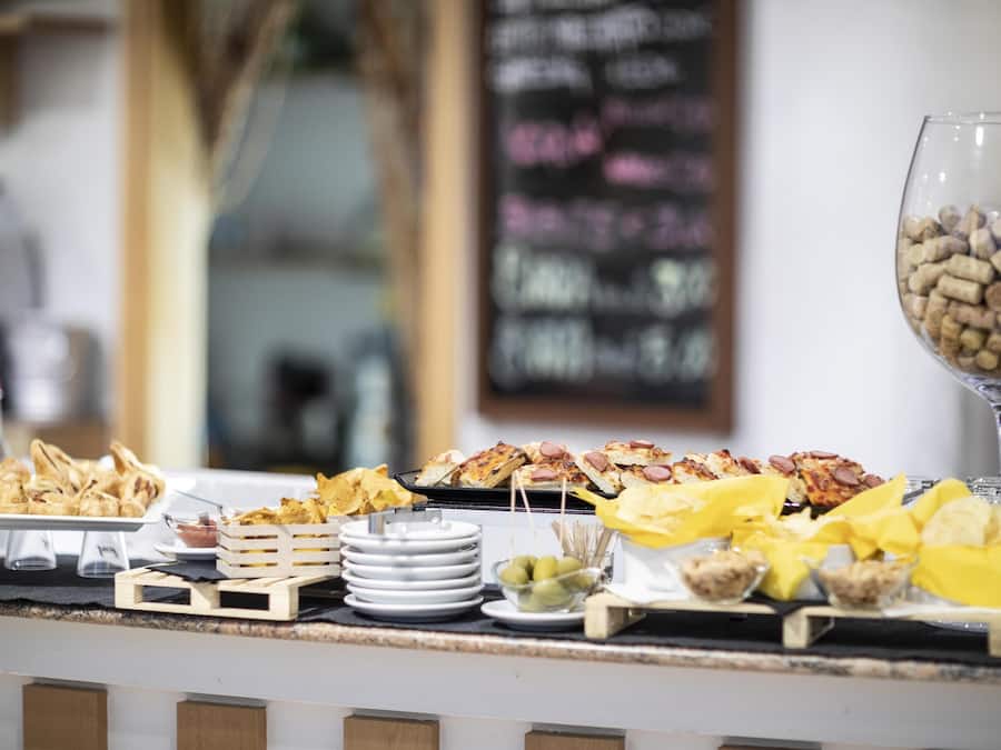 A buffet table with various food items and a wine glass.