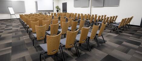Un salón de conferencias con filas de sillas de madera y piso alfombrado.