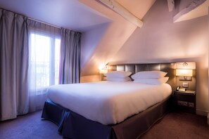 A hotel room with a large bed, two bedside lamps, a nightstand, and a window with curtains. - Masséna Hôtel (Paris)
