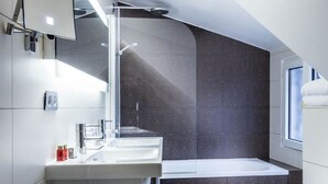 A modern bathroom with a large bathtub, a sink, and a mirror. - Masséna Hôtel (Paris)
