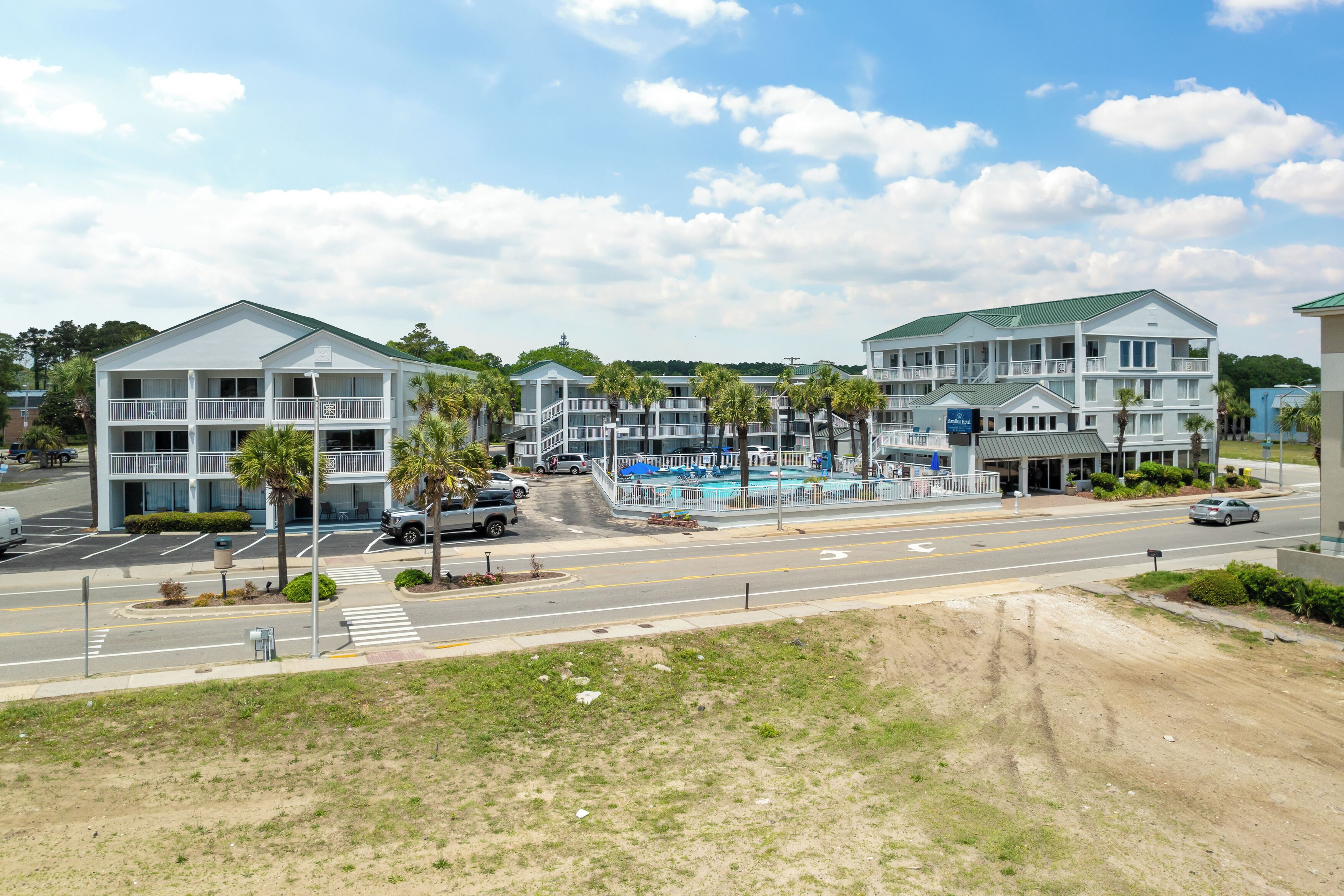 Un hôtel situé en bord de mer, doté de nombreux balcons, d’une piscine et d’une route au premier plan.