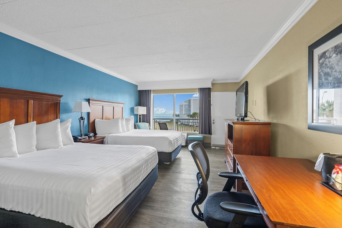 Habitación de hotel con dos camas, un escritorio y vistas a la ciudad.