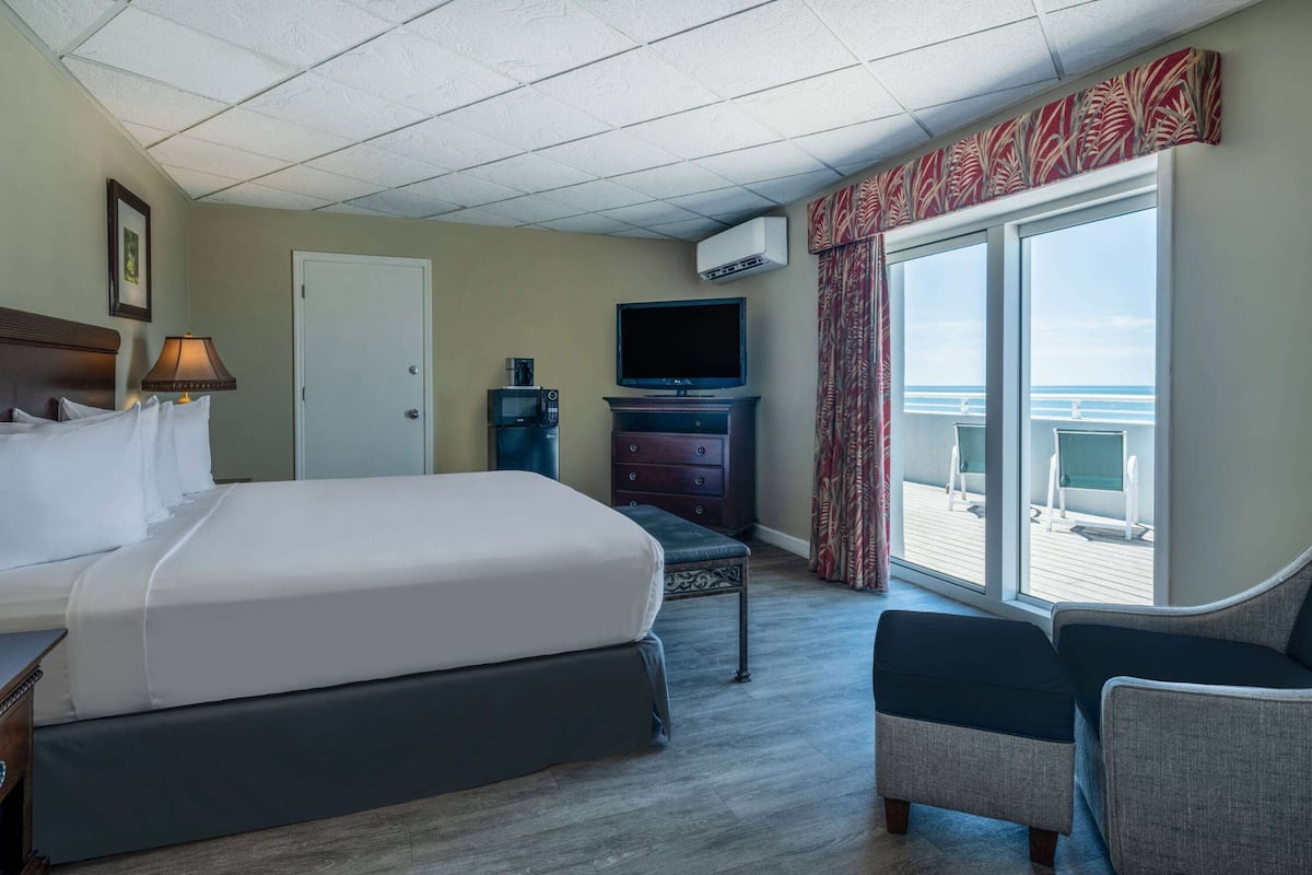 Una habitación de hotel con una cama grande, televisión, cómoda y balcón con vistas.