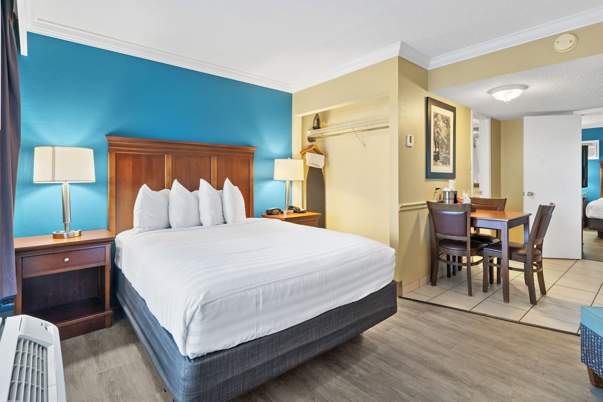 Habitación de hotel con una cama grande, un escritorio con dos sillas, una lámpara y un aparador.