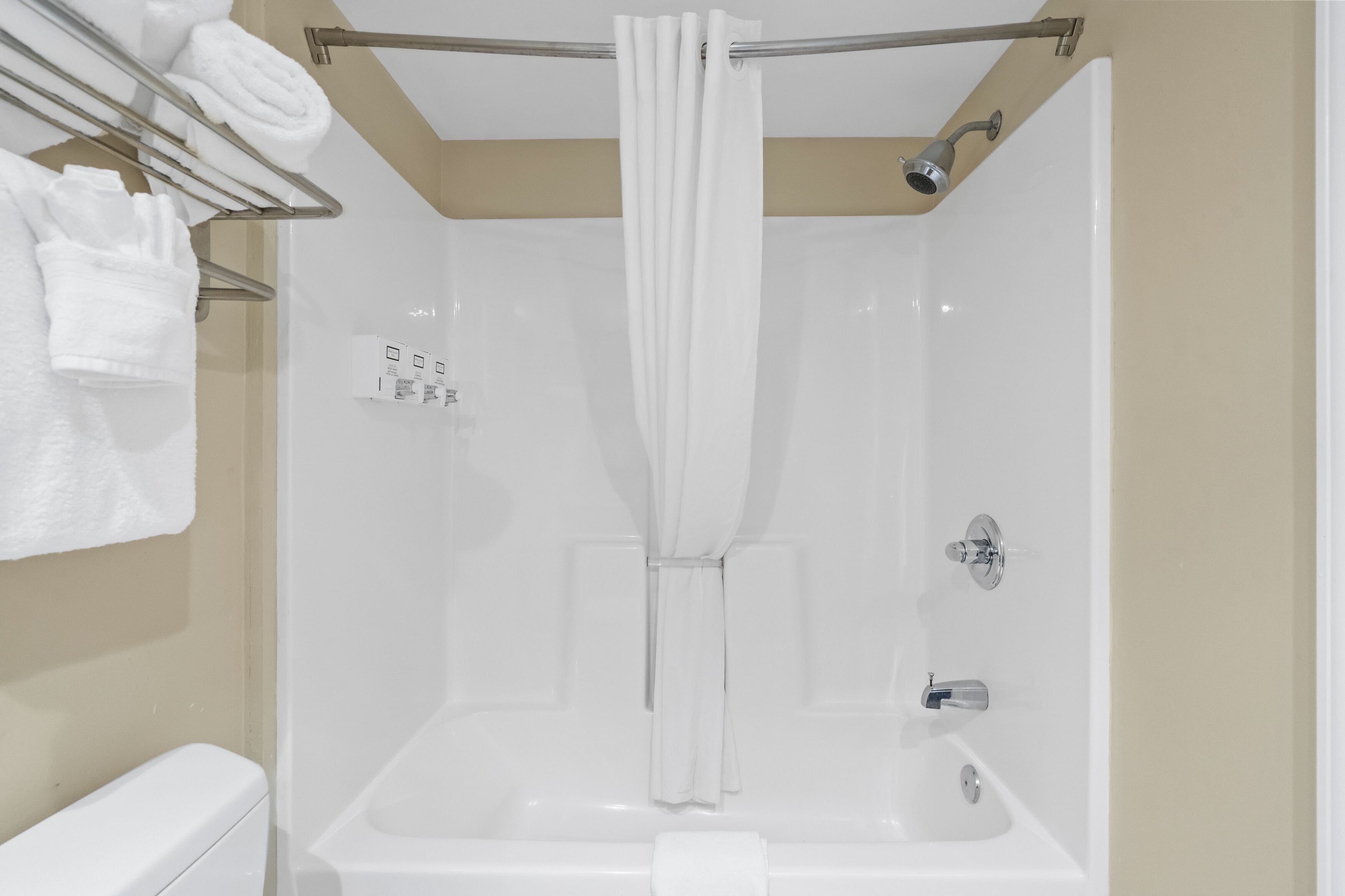 A modern bathroom with a walk-in shower, a toilet, and a towel rack with folded towels.