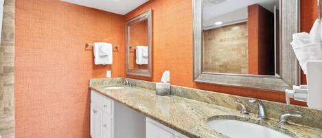 A modern bathroom with two sinks, a large mirror, and a towel rack.