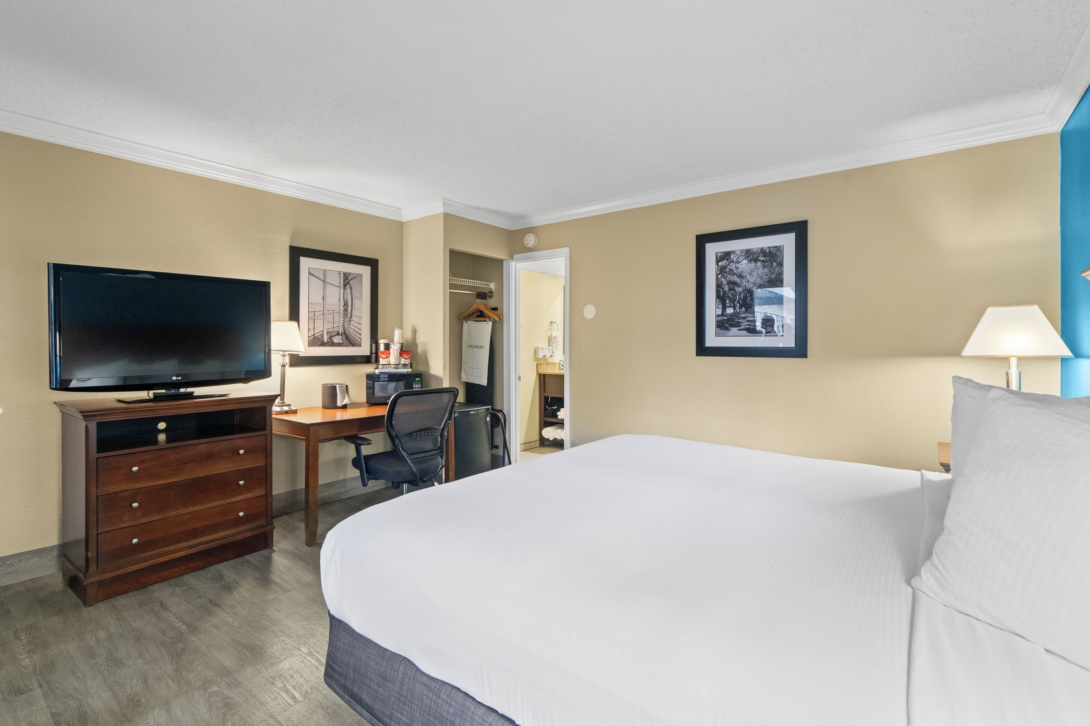 Une chambre d’hôtel avec un grand lit, un bureau avec un ordinateur, une télévision et une armoire.