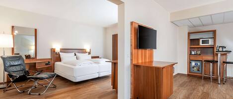 Una habitación de hotel moderna con cama, escritorio, televisor, microondas y minibar.