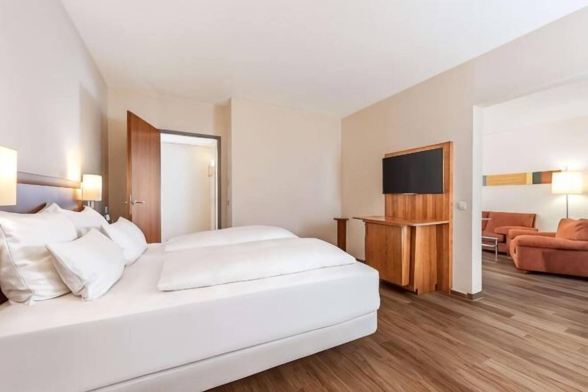 A hotel room with a bed, a TV, a desk, and a seating area.