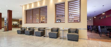 A modern lobby with seating areas, a reception desk, and a bar.