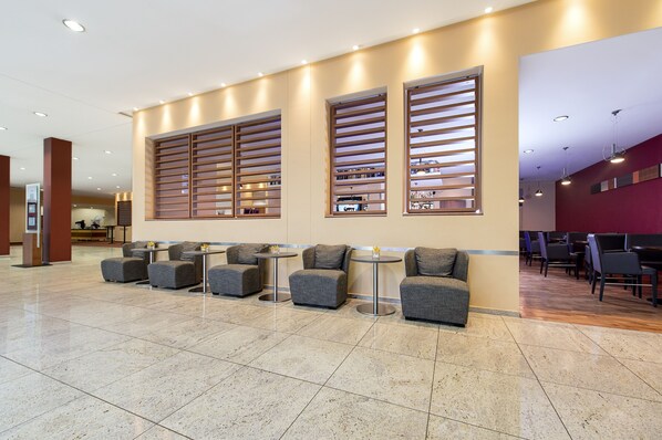 A modern lobby with seating areas, a reception desk, and a bar.