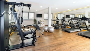 A gym with exercise equipment, treadmills, and a mirrored wall. - NH München Ost Conference Center (Aschheim)