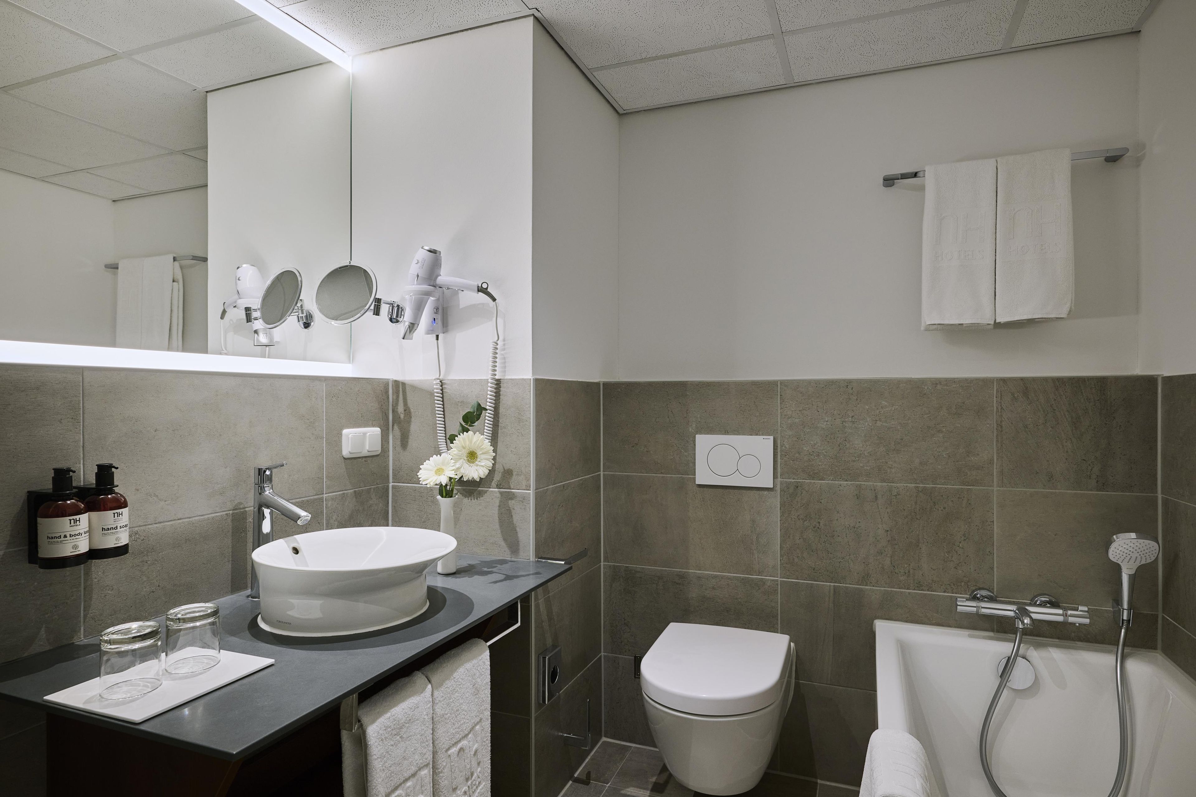 A modern bathroom with a large mirror, a round sink, a toilet, and a shower area.