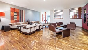 A spacious living area with a sofa set, a coffee table, and a dining table with chairs. - NH München Ost Conference Center (Aschheim)