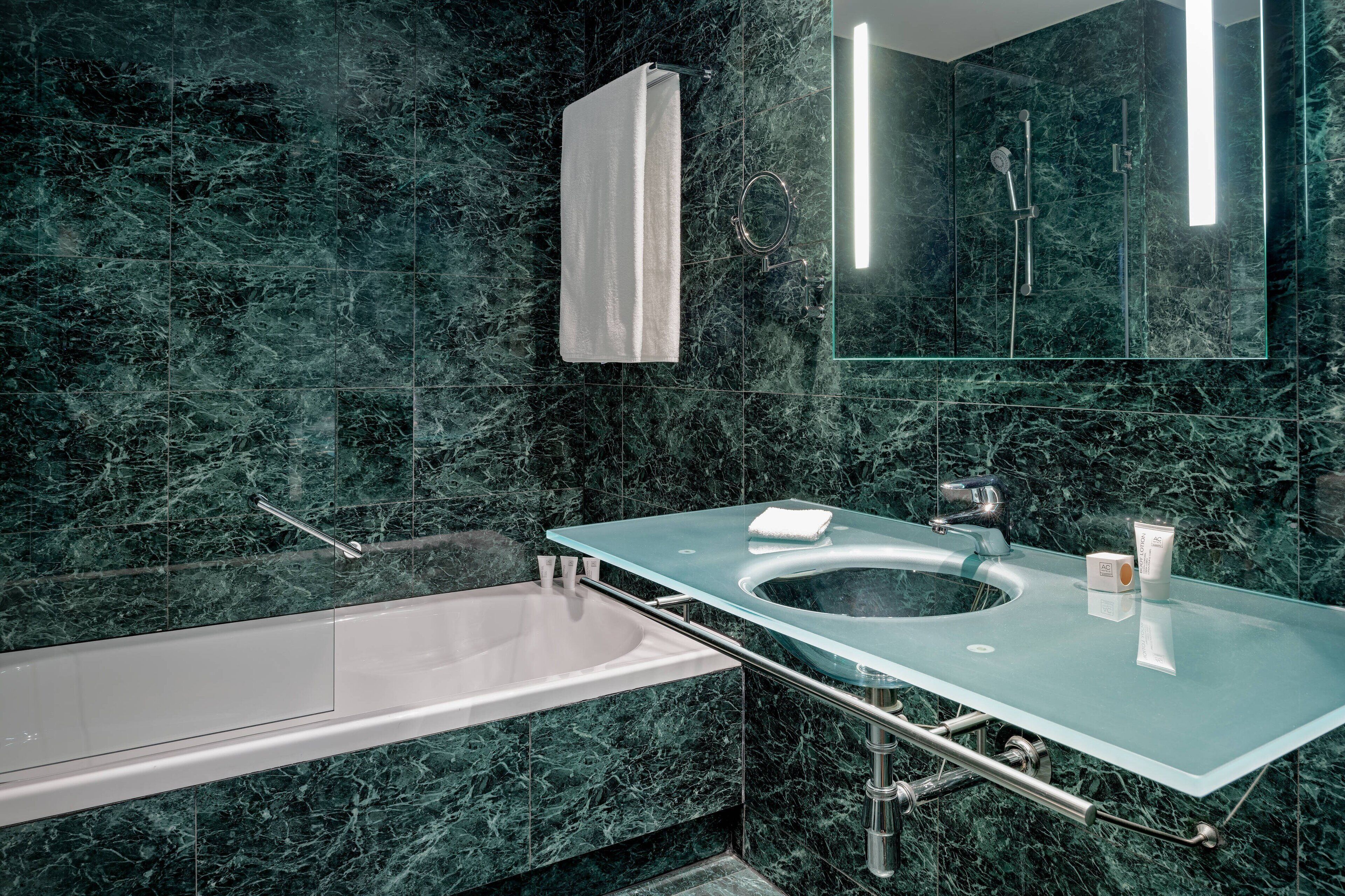 A bathroom with a glass sink, a bathtub, and a large mirror.