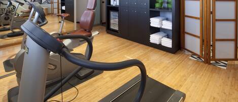 A gym with exercise equipment, a seating area, and a storage cabinet with towels.
