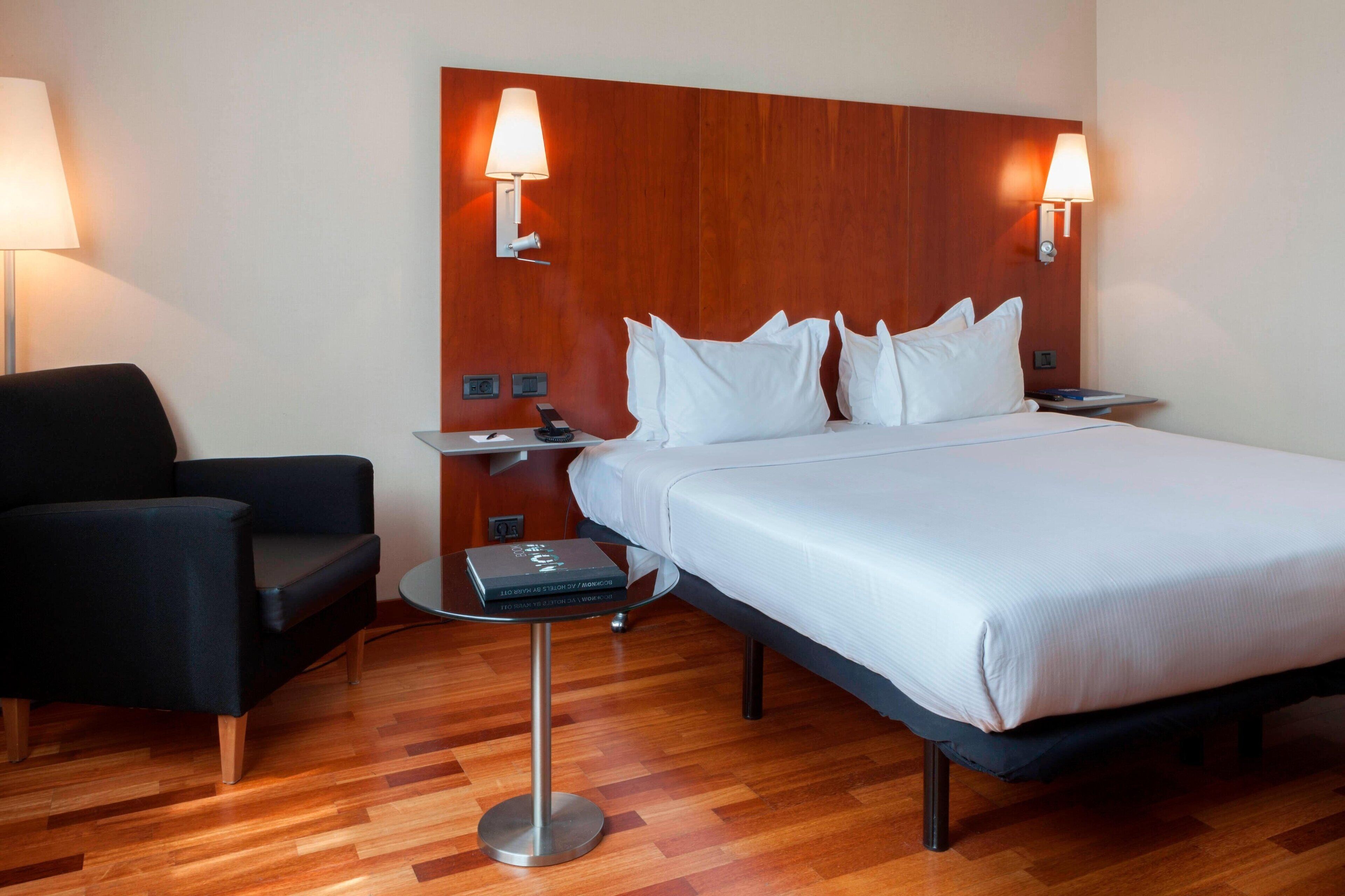 A hotel room with a bed, two bedside tables, a chair, and a lamp.