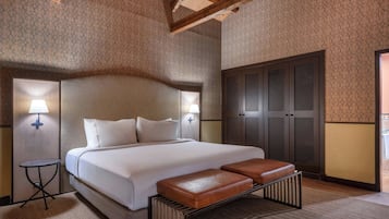 Une chambre d’hôtel avec un grand lit, deux lampes de chevet, une armoire et un banc.