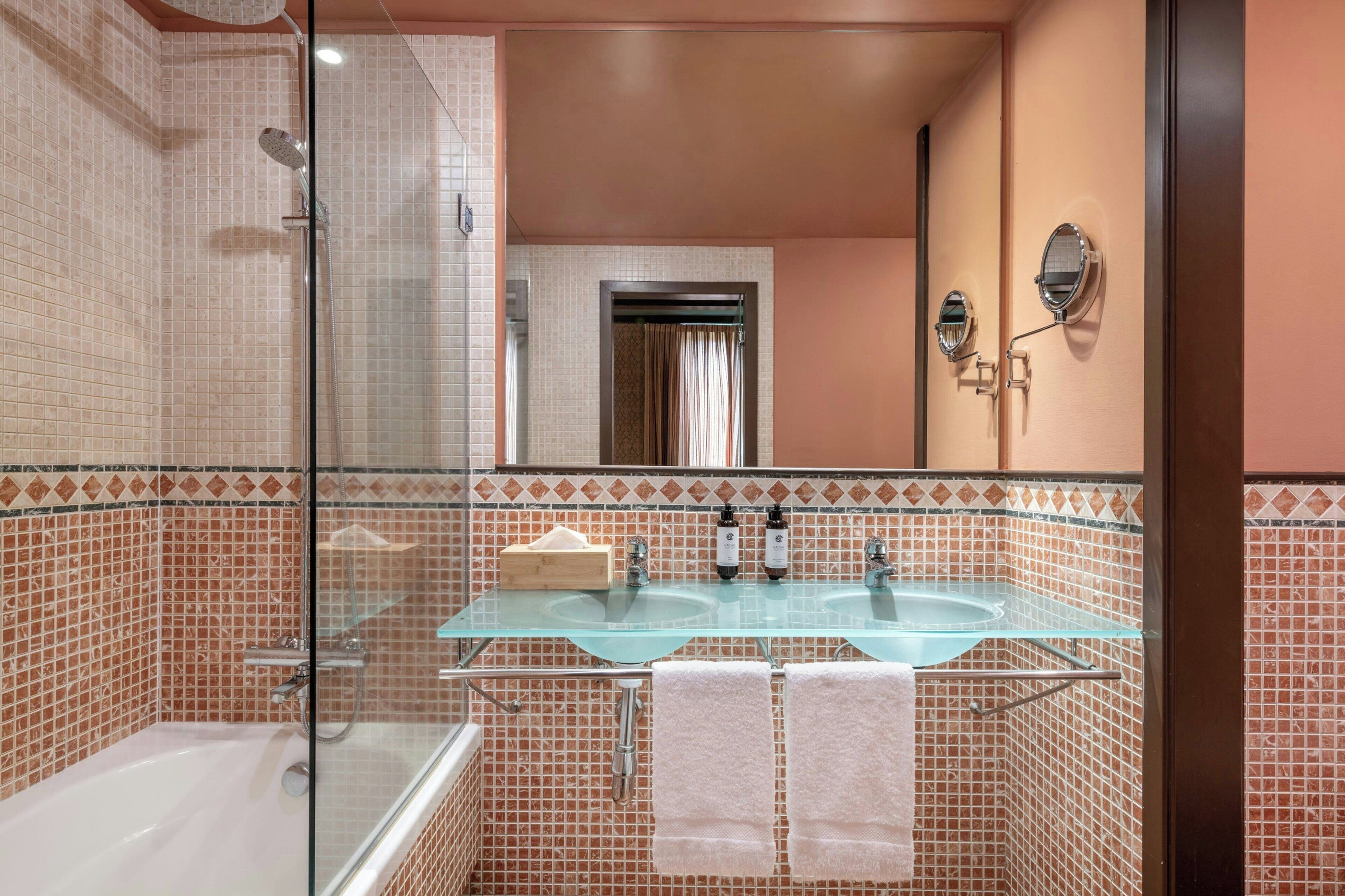 Ein Badezimmer mit zwei Waschbecken aus Glas, einer Badewanne und einer Dusche.