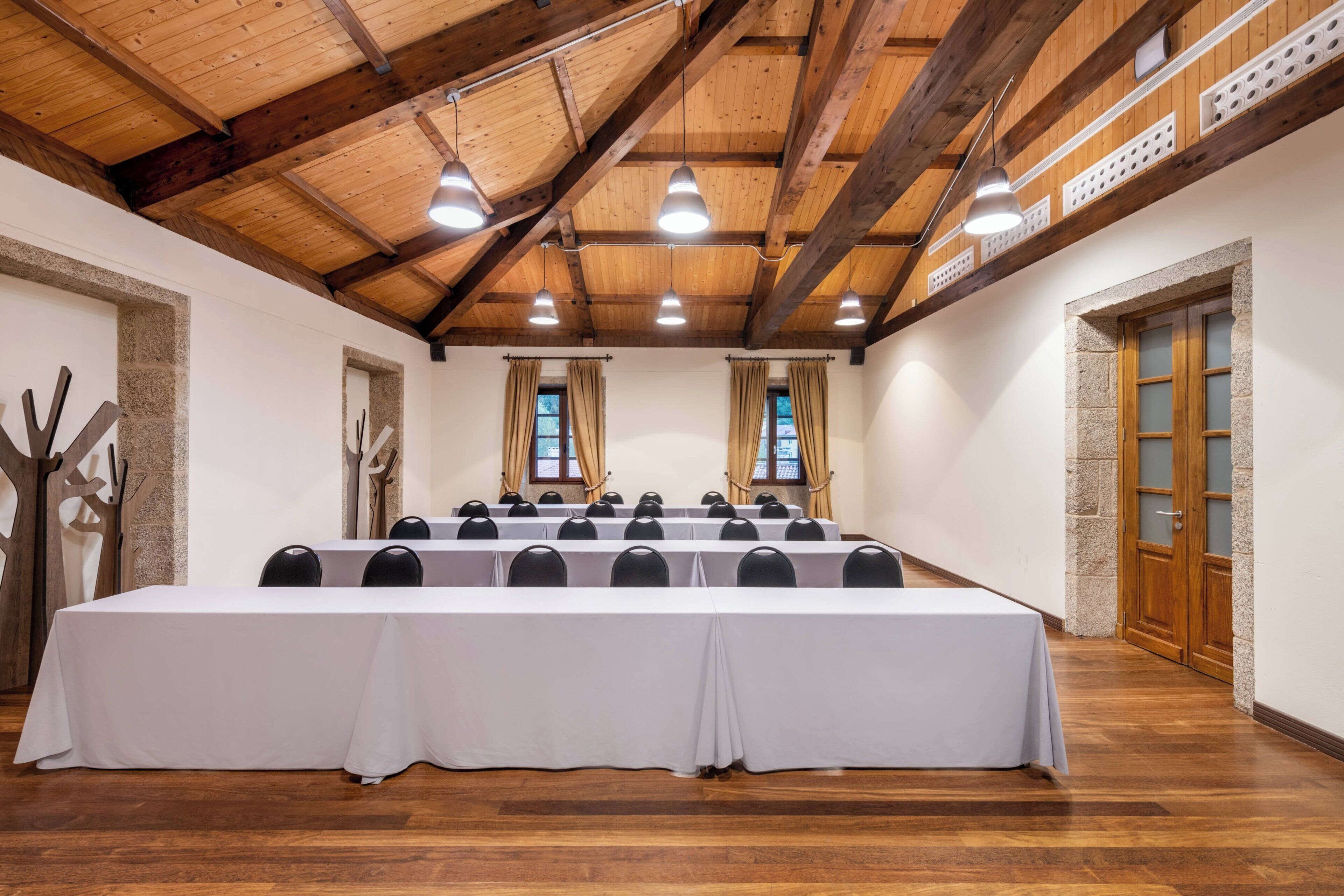 Una sala de conferencias con una mesa larga, varias sillas, vigas de madera y una pared de piedra.