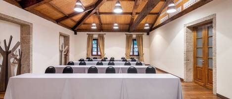 A conference room with a long table, multiple chairs, wooden beams, and a stone wall.
