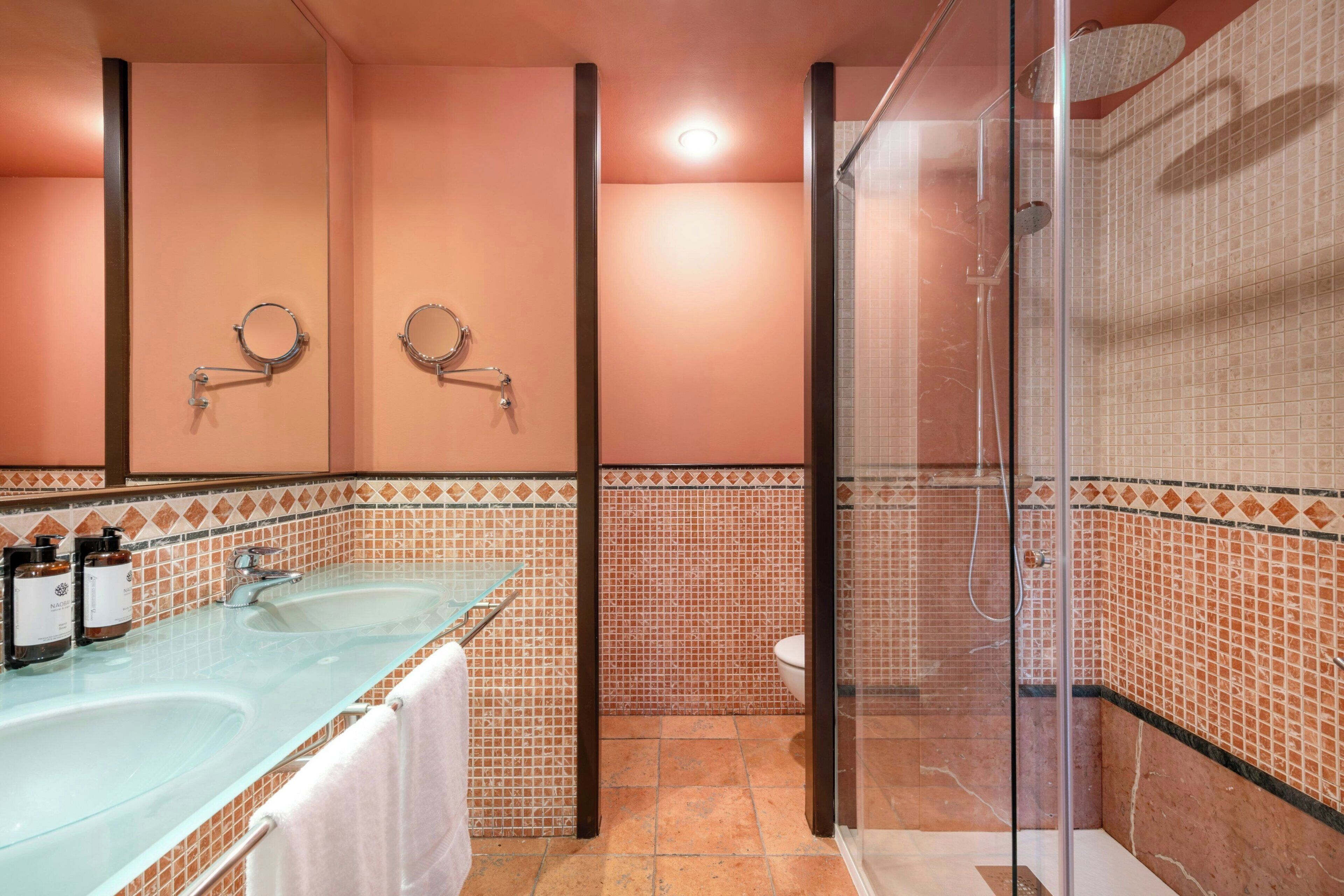 Een badkamer met een douchecabine van glas, een wastafel met een handdoek en een toilet.