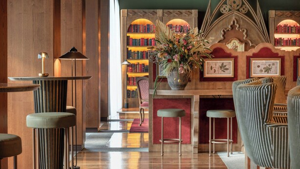 Une bibliothèque avec des étagères, une table centrale ornée d’un vase de fleurs et des coins salon.