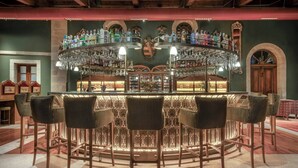 Un espace bar doté d’un comptoir circulaire, de nombreux tabourets et d’une grande variété de bouteilles et de verres.