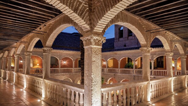 An interior courtyard with arches and columns, featuring a tiled floor and a view of the outside at dusk. - Hotel Palacio de Santa Paula, Autograph Collection (Granada)
