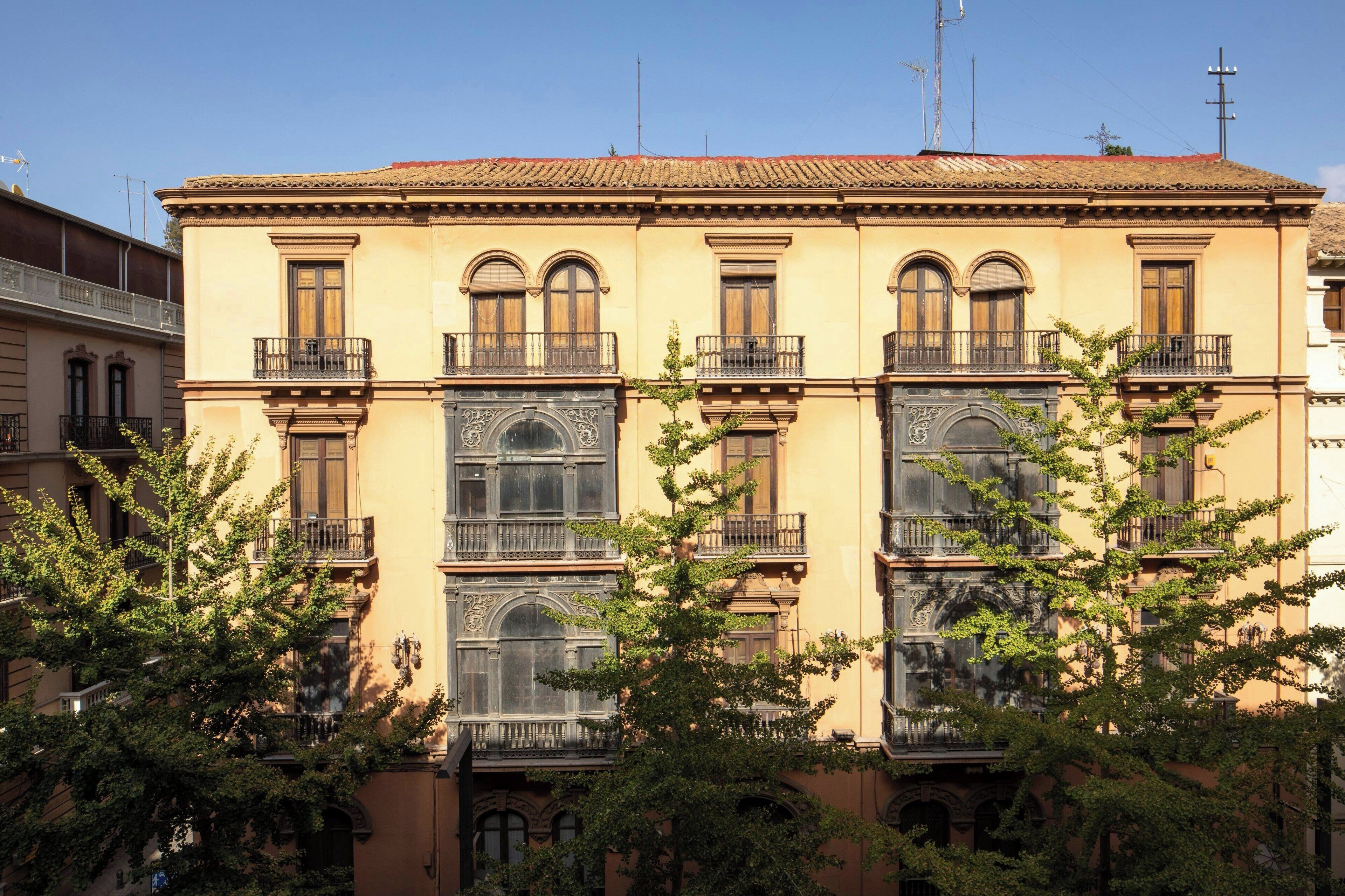 Un edificio de varios pisos con balcones ornamentados y grandes ventanales.