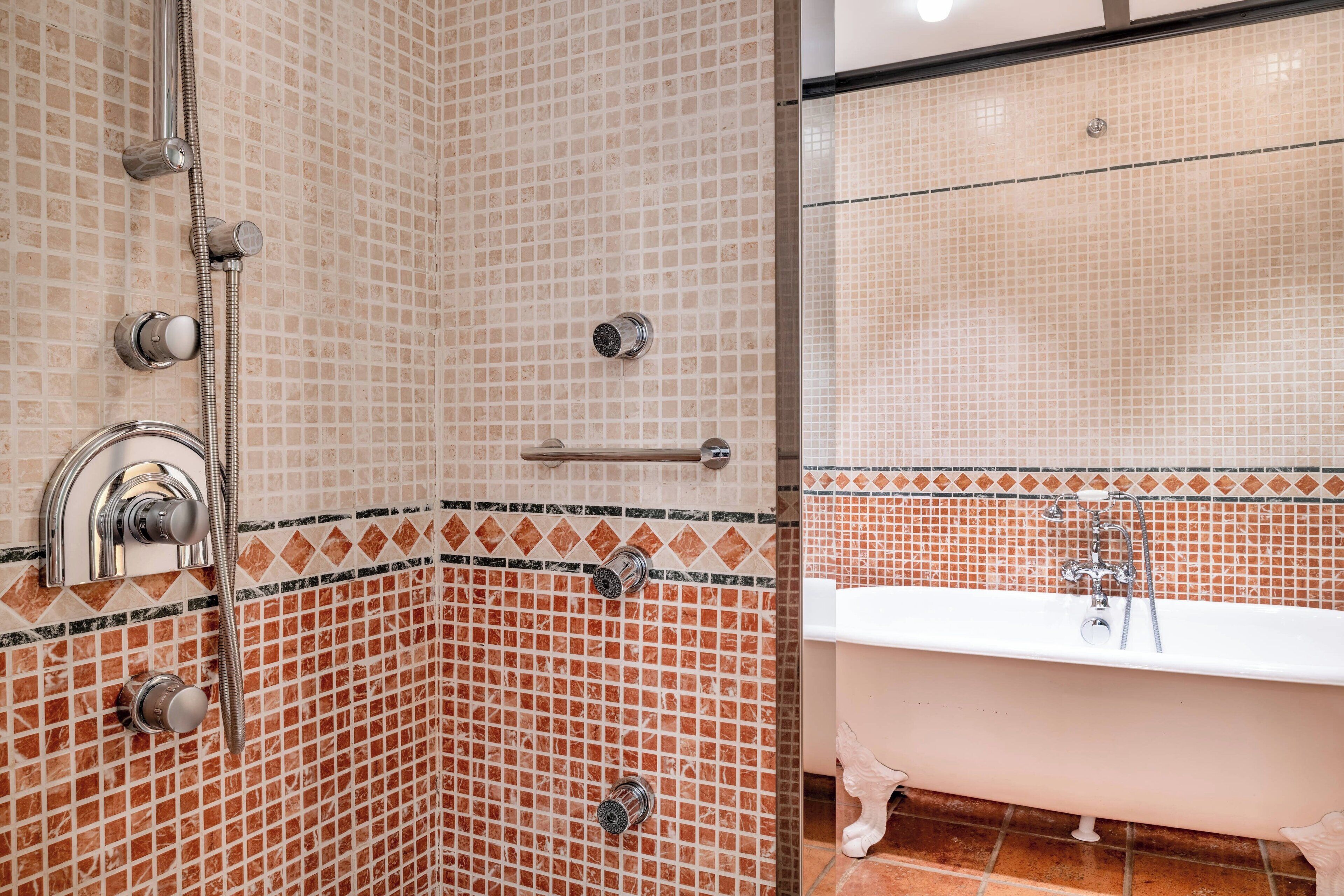 Un baño con ducha, bañera y paredes de azulejos.