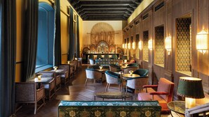 A restaurant with wooden beams, patterned wallpaper, and a variety of seating including chairs and a sofa. - Hotel Palacio de Santa Paula, Autograph Collection (Granada)