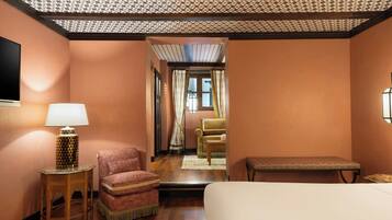 Une chambre d’hôtel avec un lit, une chaise, une petite table avec une lampe et un banc.