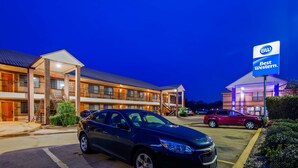 A multi-story hotel with a parking lot, a Best Western sign, and a red car parked in the lot. - Best Western Executive Inn (Marshall)