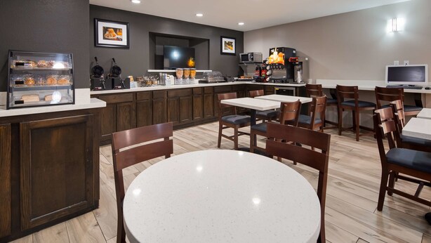 A modern cafe with wooden cabinets, a coffee machine, and a TV mounted on the wall. - Best Western Executive Inn (Marshall)
