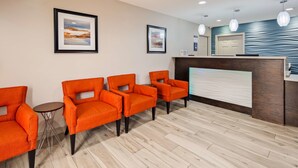 A reception area with four orange chairs, a reception desk, and two framed abstract paintings on the wall. - Best Western Executive Inn (Marshall)