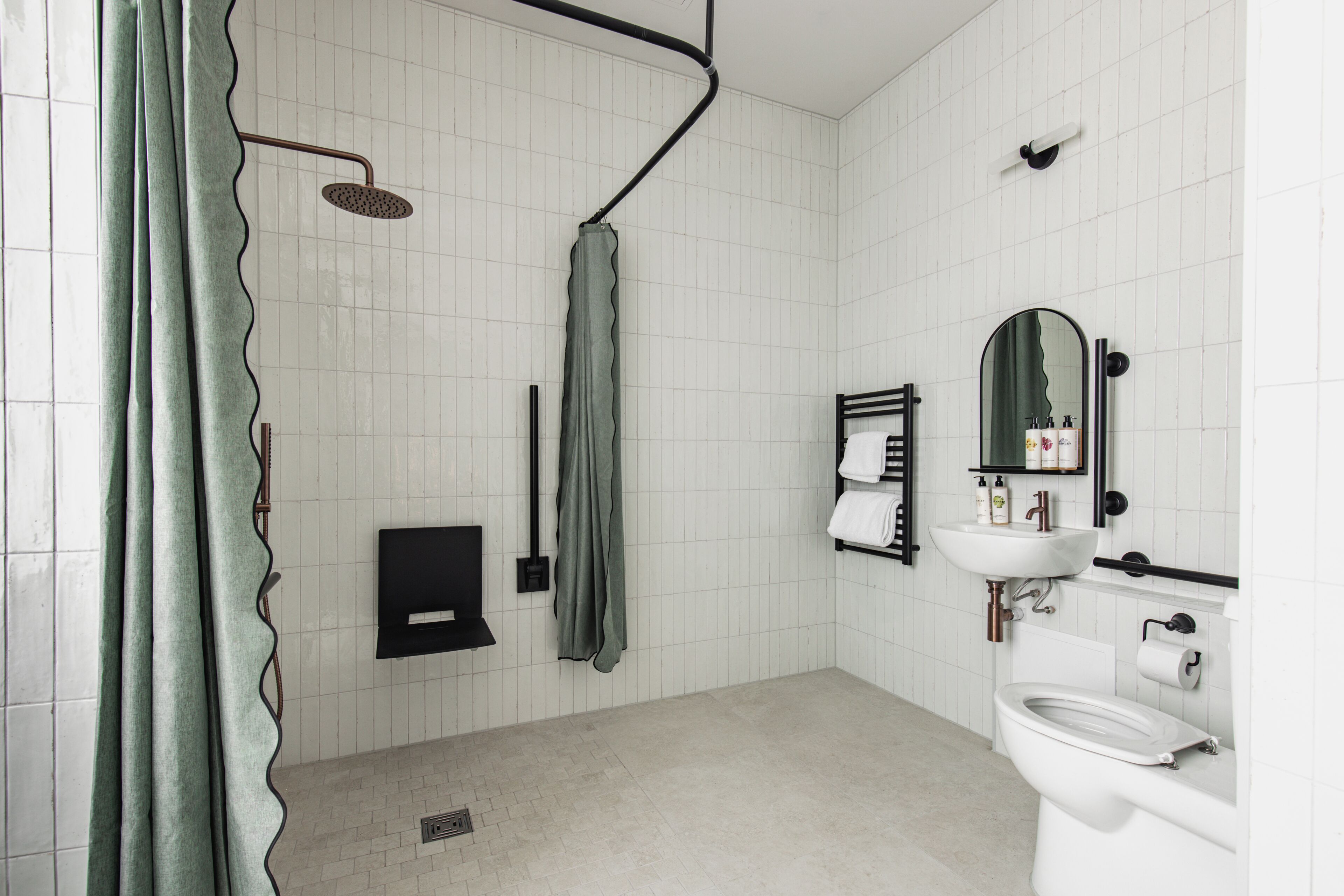 A bathroom with a shower, toilet, sink, and mirror.
