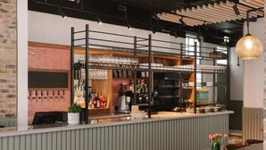 Eine Bar mit Theke, Regalen voller Gläser und einer Ziegelwand.