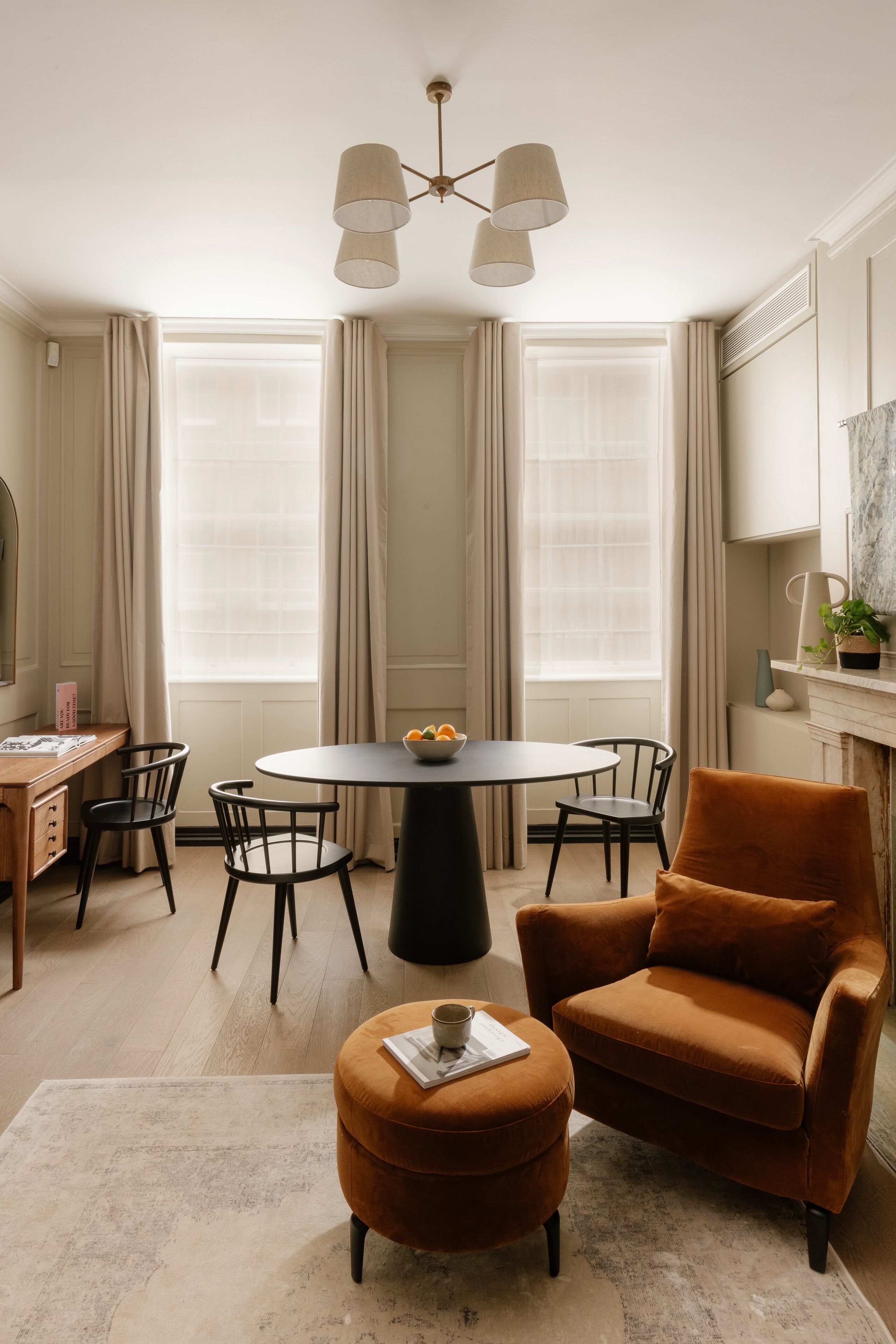 A modern dining area with a round table, chairs, and a pendant light.