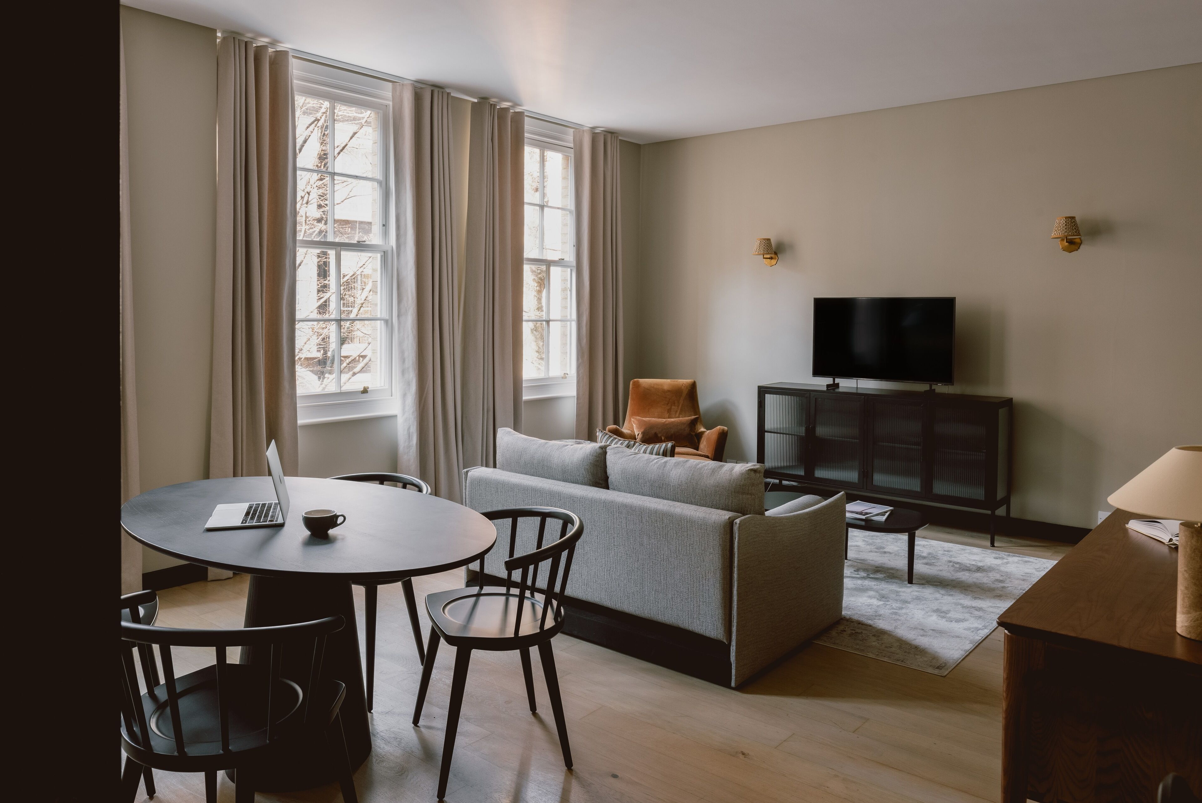 Un salon moderne comprenant un canapé, un téléviseur, une table à manger avec des chaises et un ordinateur portable.