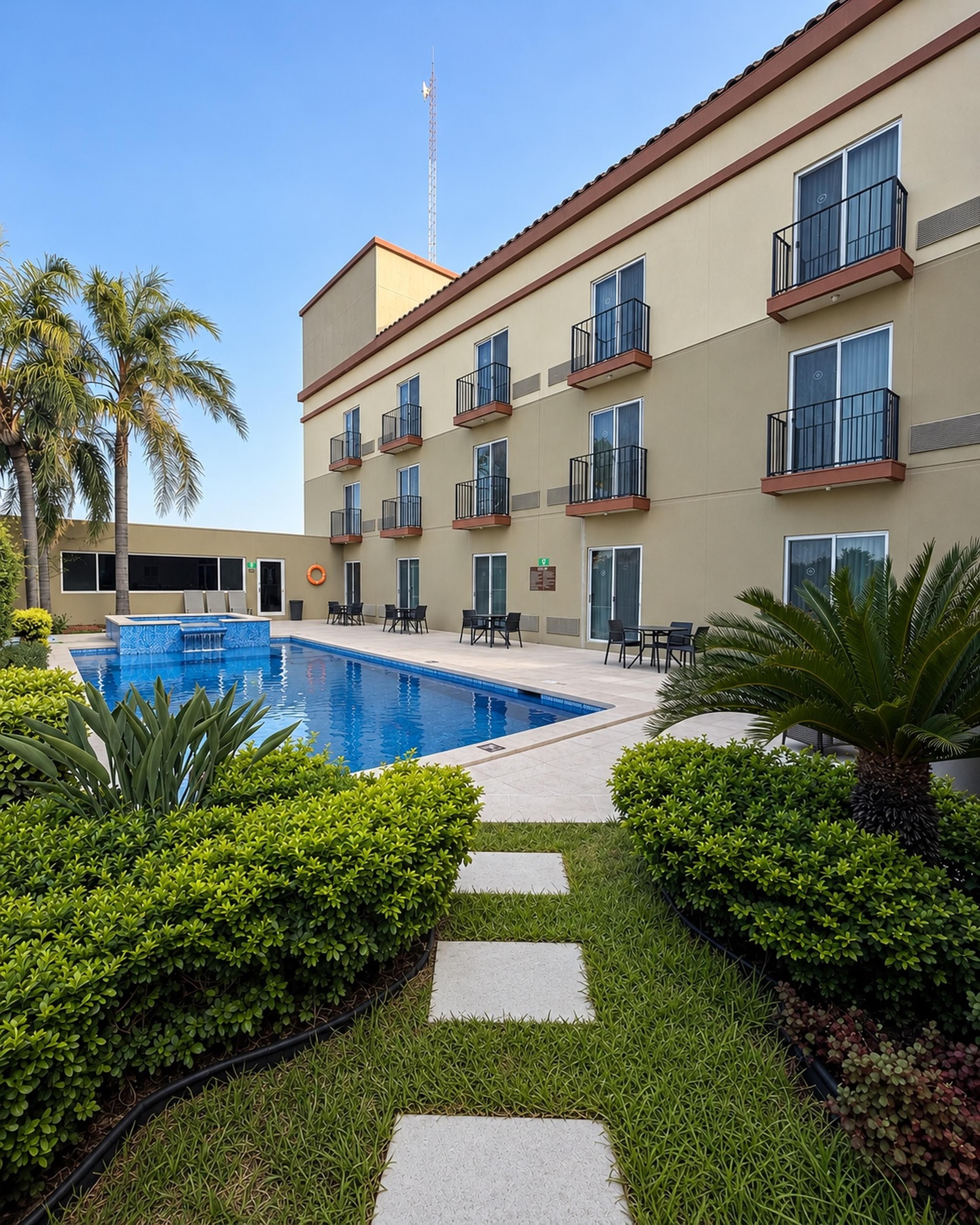 Un hotel con piscina, mobiliario exterior y palmeras.