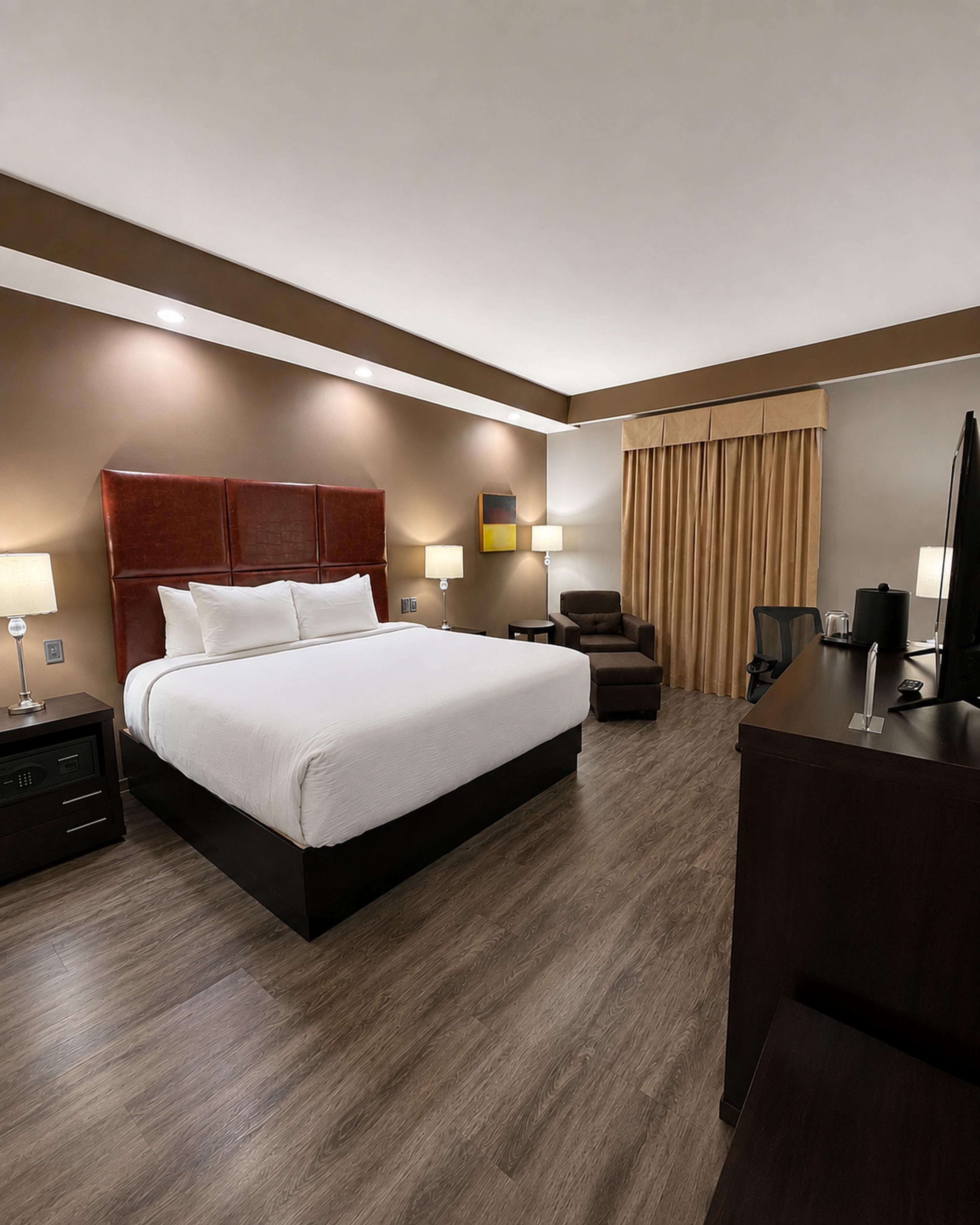 A hotel room with a large bed, a desk, a chair, and a television.