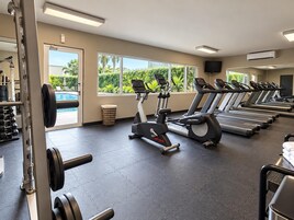 Un gimnasio con cintas de correr, bicicletas estáticas y equipo de levantamiento de pesas.