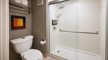 A bathroom with a toilet, a shower with a glass door, and a towel rack with towels.