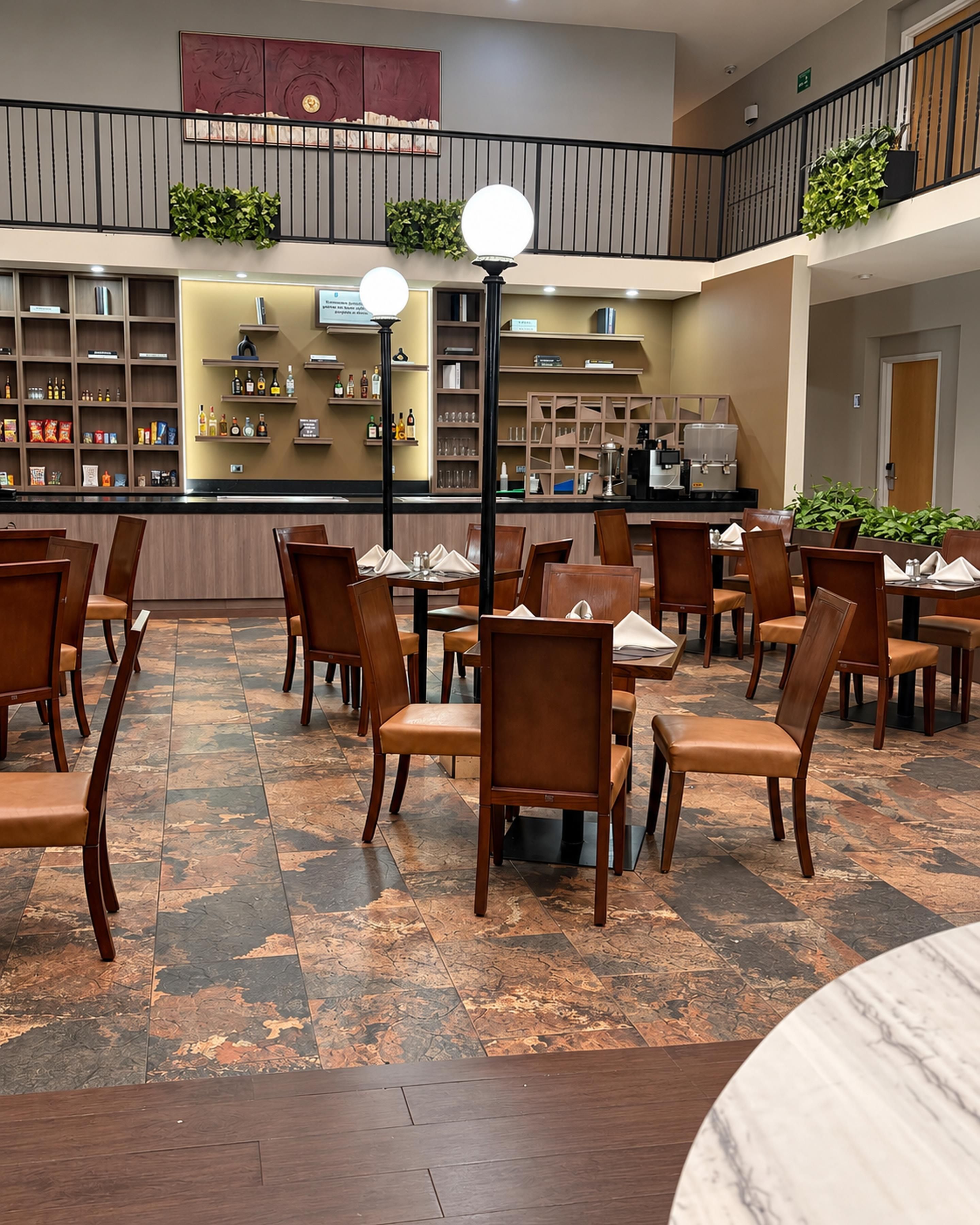 A hotel lobby with a dining area, a bar, and a staircase.