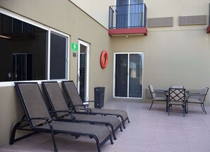 Un edificio con un espacio de estar al aire libre cubierto, que incluye sillones y una mesa.
